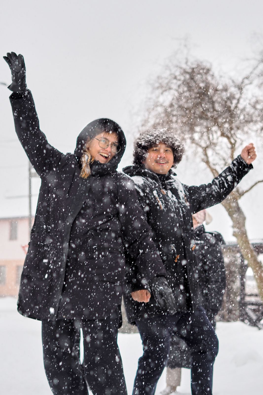 Two people celebrating with raised arms in heavy snowfall